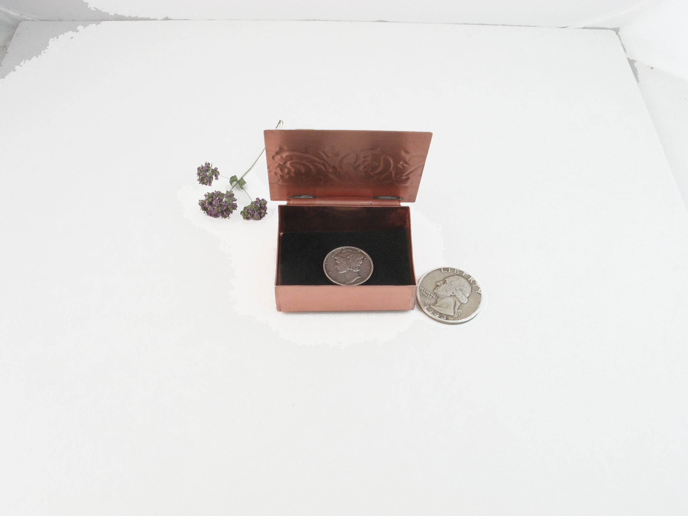 inside of tiny trinket box showing black felt lining and size related to dime and quarter