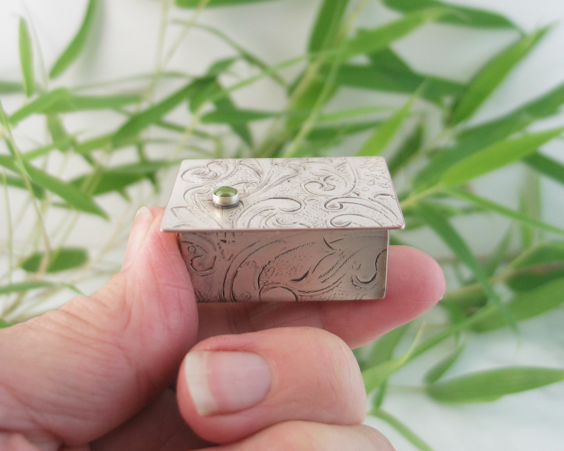 Miniature Silver Trinket Box with peridot gemstone, held by fingers