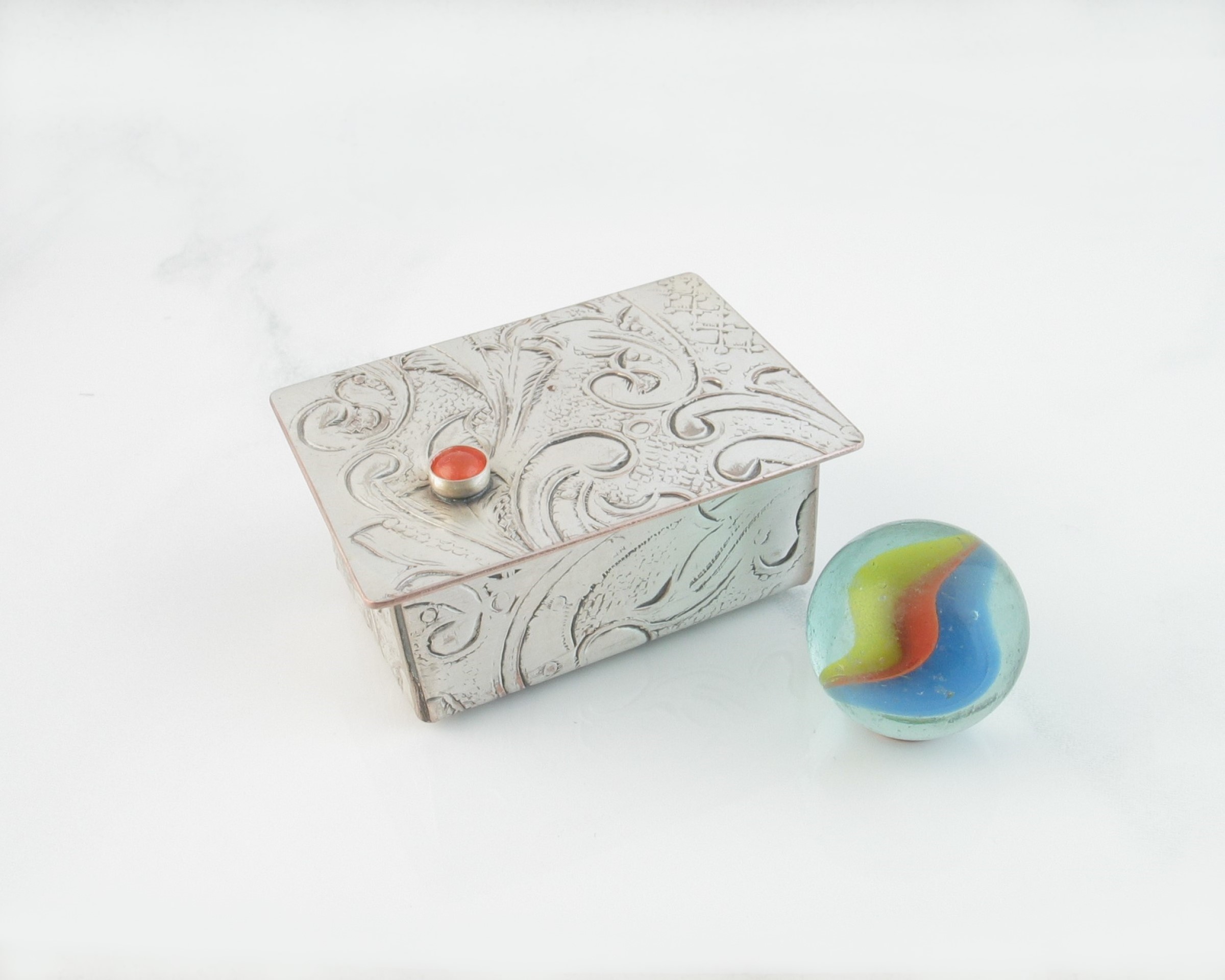 Miniature Silver Trinket Box with Carnelian gemstone, shown with a small cat eye marble for size comparison
